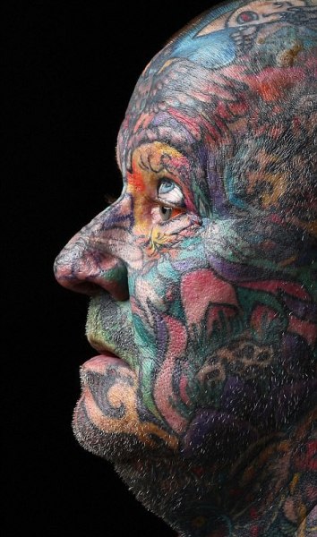 An elderly man with a full face tattoo.